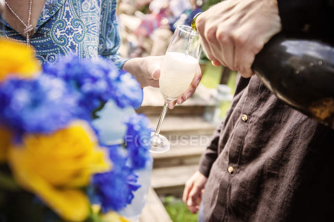 Homem derramando champanhe para a mulher na festa do jardim — Fotografia de Stock