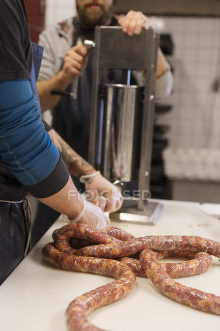 Hommes utilisant un hachoir à viande pour remplir les boyaux de saucisses de porc haché — Photo de stock