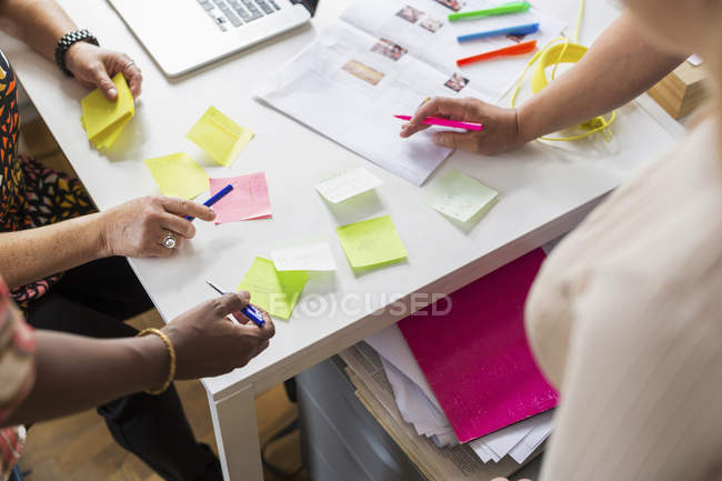 Colaboradores escrevendo em notas adesivas durante a reunião — Fotografia de Stock