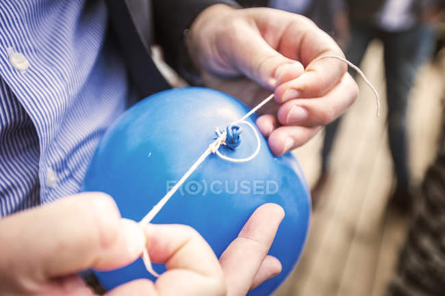 Imagen recortada de la persona atando nudo en globo, primer plano - foto de stock