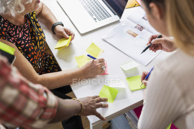 Coworkers writing on adhesive notes during meeting — Stock Photo