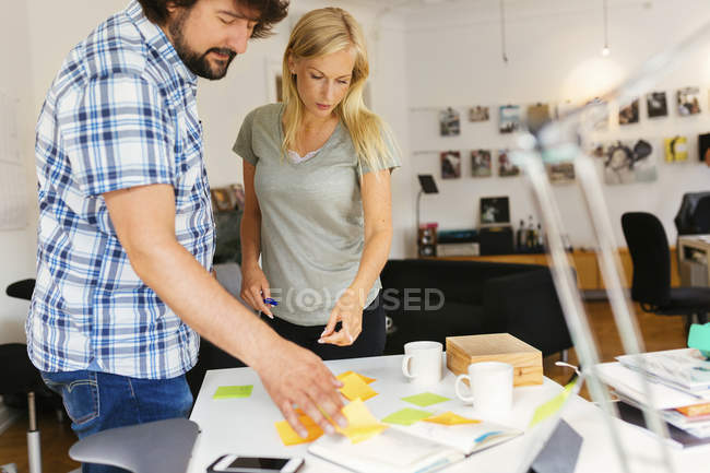 Editors using notepad and adhesive notes during discussion on project — Stock Photo