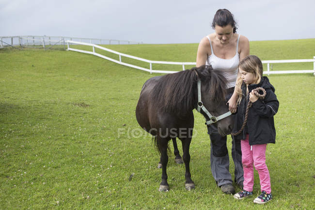 Mother and daughter (4-5) standing with pony — Stock Photo
