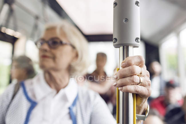 Femme âgée tenant la main courante dans le bus — Photo de stock