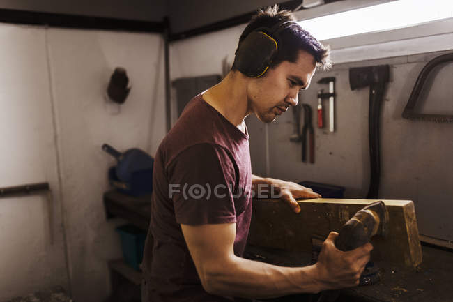 Чоловік полірує деревину в гаражі — стокове фото