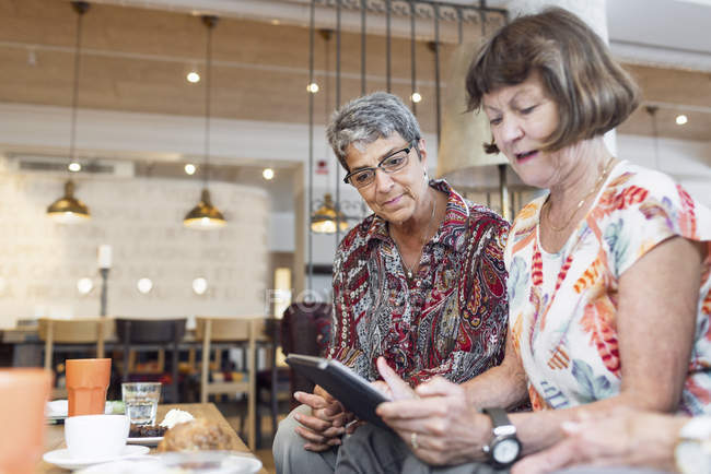 Дві жінки використовують цифровий планшет у кафе — стокове фото