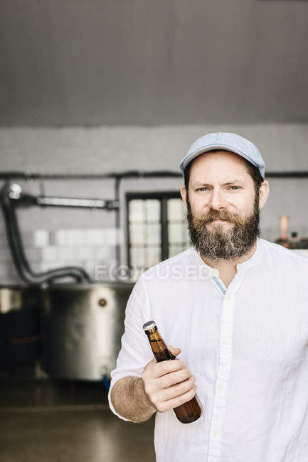 Porträt eines bärtigen Brauereiarbeiters, der Bier hält — Stockfoto