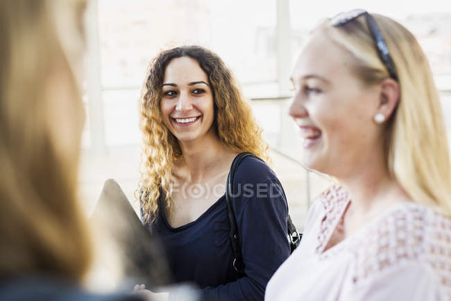 Молоді жінки сміються, дивлячись один на одного — стокове фото