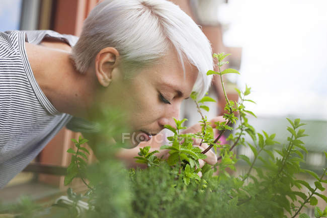 Woman smelling fresh herbs on balcony — Stock Photo