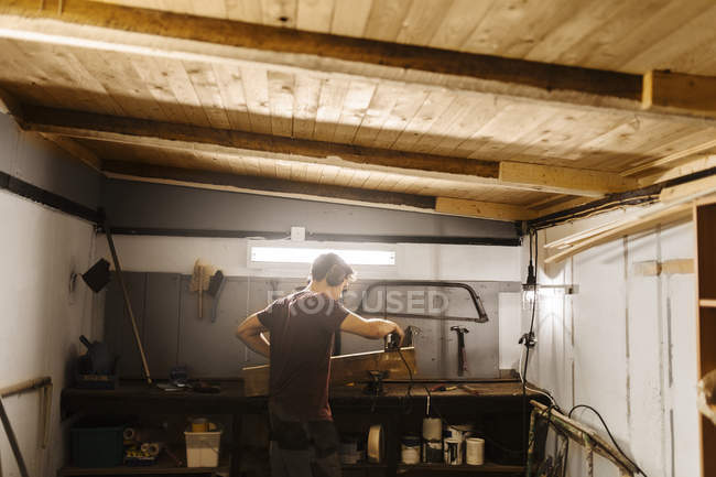 Uomo lucidatura legno in garage — Foto stock
