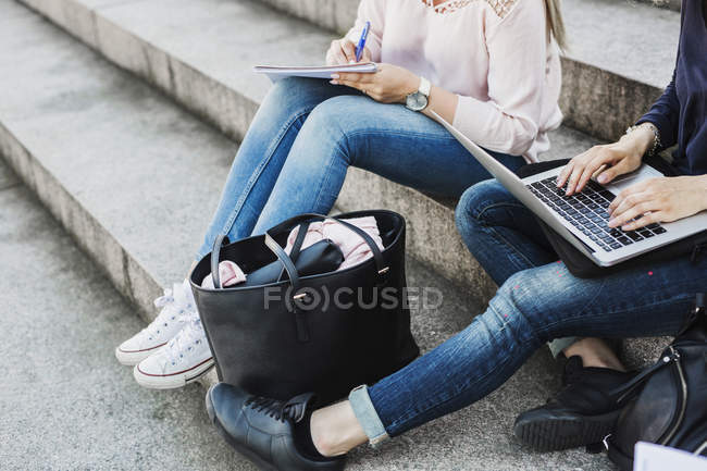 Молода жінка використовує ноутбук, сидячи на сходах — стокове фото