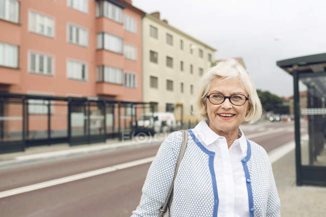 Smiling woman standing next to bus stop — Stock Photo