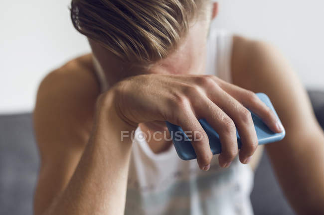 Pensive young man holding smart phone — Stock Photo