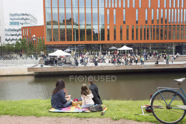 Genitori con figlia (4-5) godendo picnic con concerto in background — Foto stock