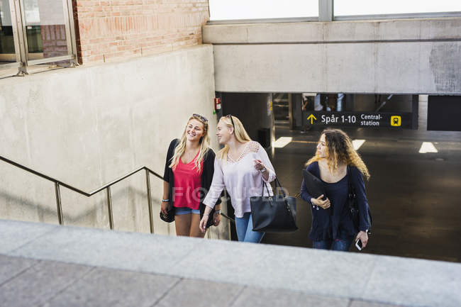 Three young women walking up stairs — Stock Photo