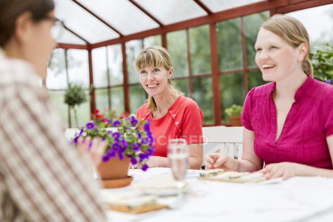 People talking at table in conservatory — Stock Photo