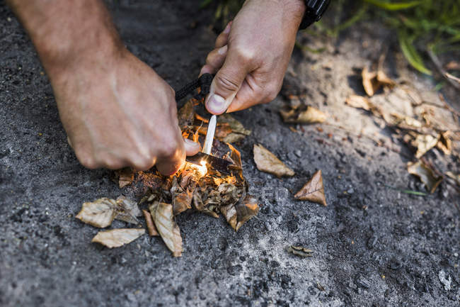 Homem acendendo fogo acampamento no chão — Fotografia de Stock