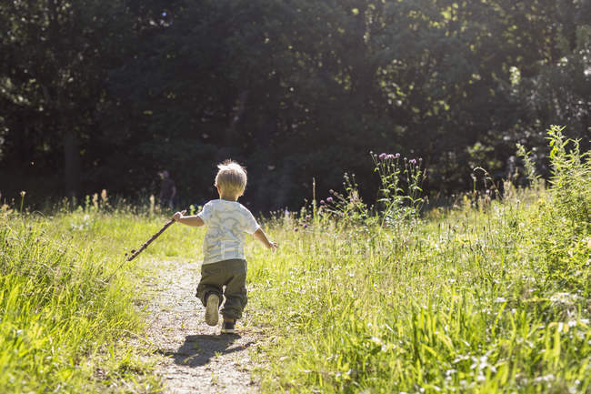 Junge (2-3) läuft auf Fußweg gegen Bäume — Stockfoto