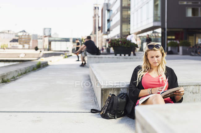Young woman reading book on street — Stock Photo