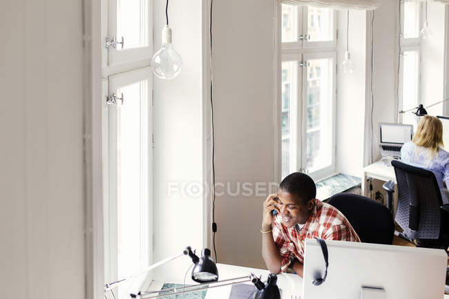 Homem falando no telefone, mulher usando o computador no escritório — Fotografia de Stock