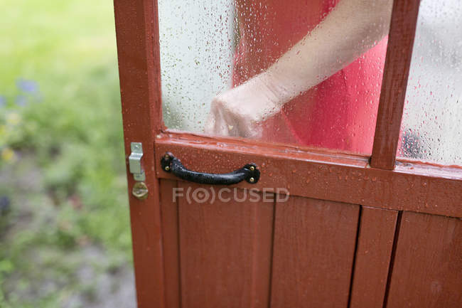 Partie médiane de la femme ouvrant une porte en bois — Photo de stock