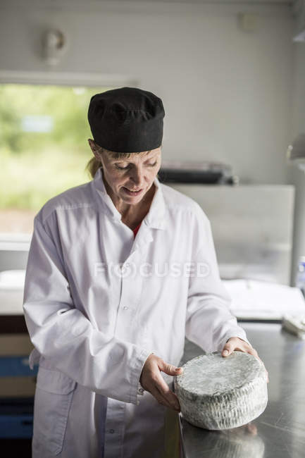 Porträt einer Frau im weißen Kittel, die Käse kontrolliert — Stockfoto