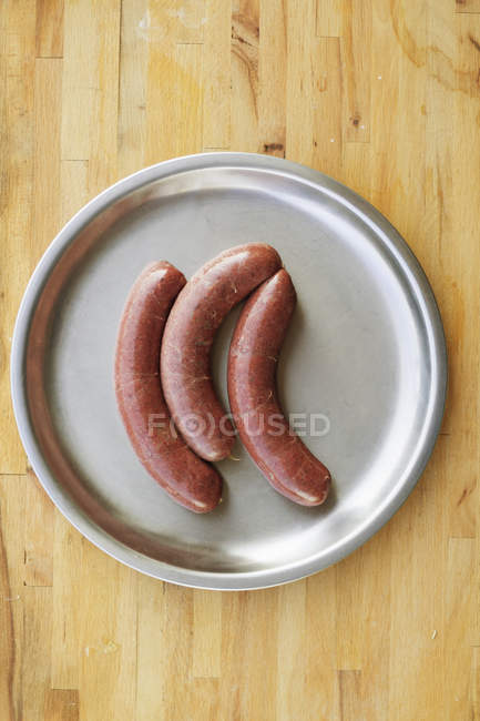 Studio shot of pork sausages on silver plate — Stock Photo