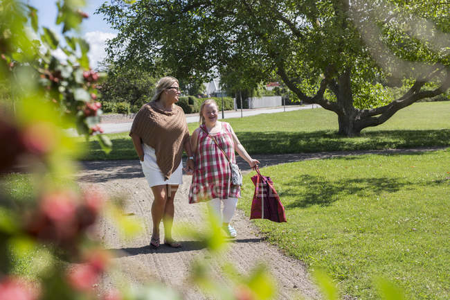 Mãe e filha com síndrome de down andando no parque — Fotografia de Stock