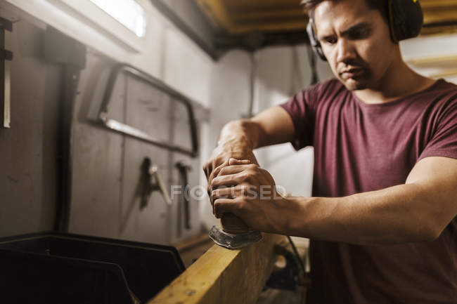 Homem polimento de madeira na garagem — Fotografia de Stock