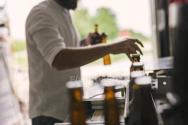 Mid section of brewery worker preparing beer bottles — Stock Photo
