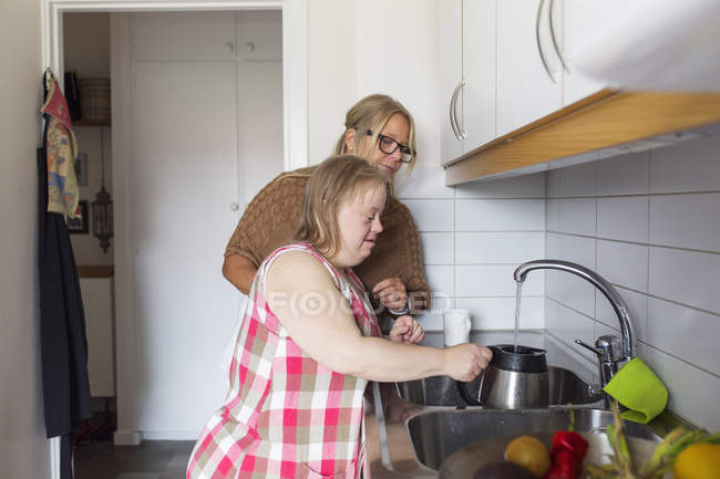 Mother and daughter with down syndrome in kitchen — Stock Photo