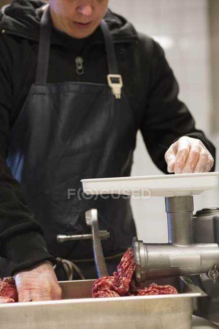 Mid section of man grinding meat to make pork sausages — Stock Photo