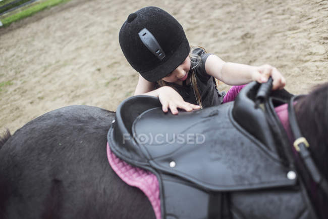 Дівчина (4-5) монтує поні на фермі — стокове фото