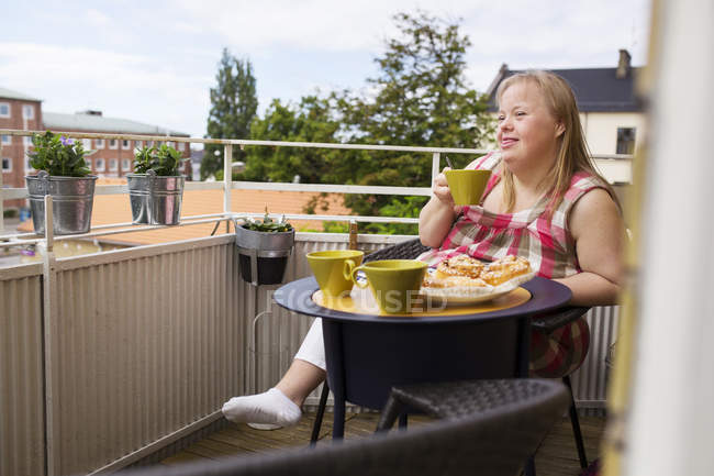 Woman with down syndrome enjoying meal on balcony — Stock Photo