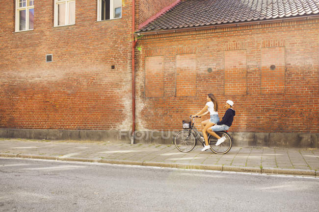 Teenage girl and teenage boy (14-15) riding bicycle together — Stock Photo