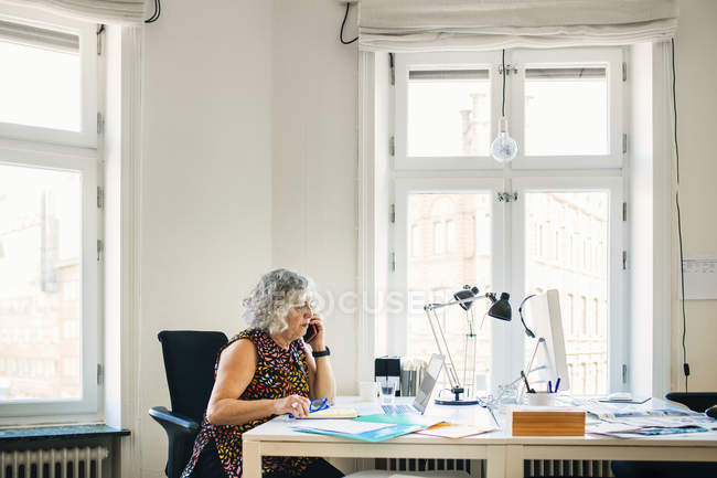 Donna d'affari che parla al telefono in ufficio — Foto stock