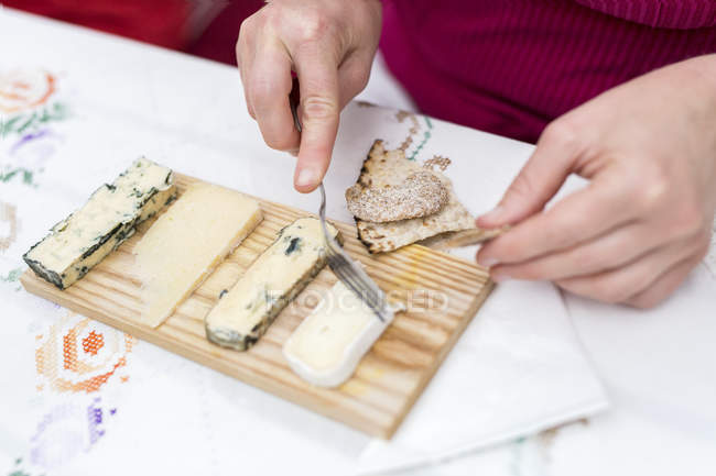 Primo piano di una donna seduta a tavola che mangia formaggio — Foto stock