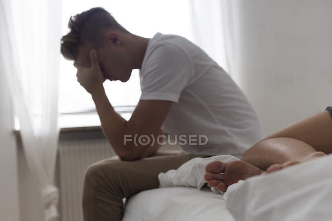 Сидящий на кровати энергичный молодой человек — стоковое фото