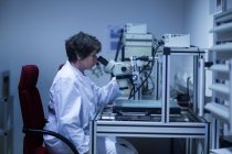 Женщина-работница смотрит в микроскоп — стоковое фото