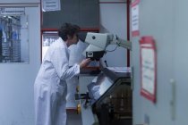 Woman in lab coat adjusting equipment — Stock Photo