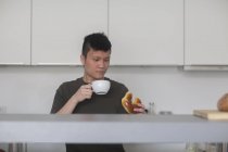 Man drinking tea with bun — Stock Photo