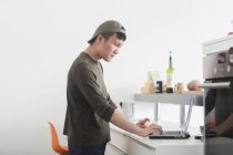 Чоловік працює на ноутбуці на кухонній стійці — стокове фото