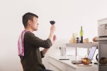 Чоловік стоїть з келихом вина на кухні — стокове фото