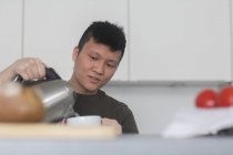 Mann schüttet kochendes Wasser in Tasse Tee — Stockfoto