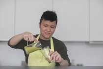 Чоловік наливає смужку в склянку на кухні — стокове фото