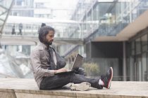 Бизнесмен сидит на парапете и работает на ноутбуке — стоковое фото