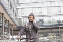 Бизнесмен разговаривает на смартфоне во время езды на велосипеде — стоковое фото