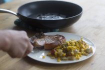 Person schneidet Steak auf Teller — Stockfoto