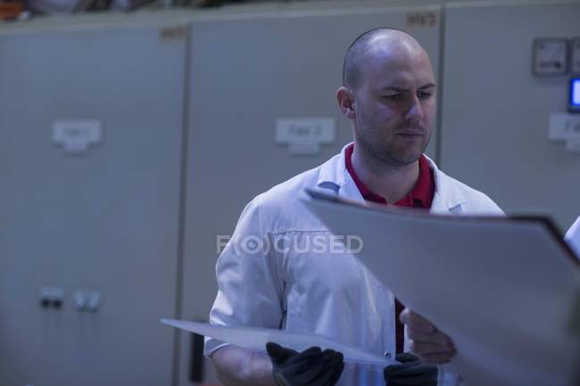 Hombre con bata de laboratorio hablando con su compañero de trabajo - foto de stock