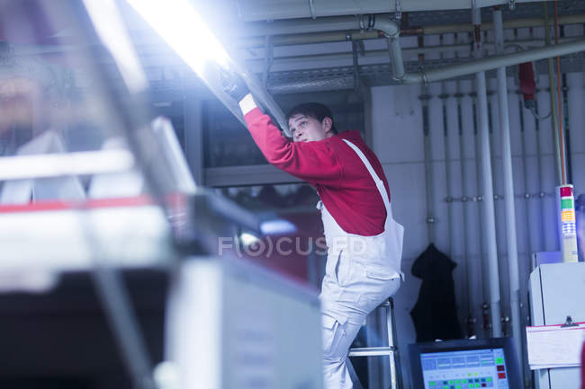 Man in uniform changing fluorescent lamp — Stock Photo